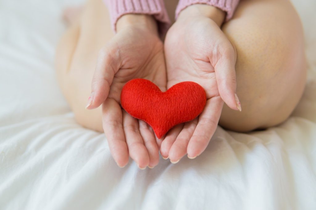 Female kneeling and holding a toy heart.