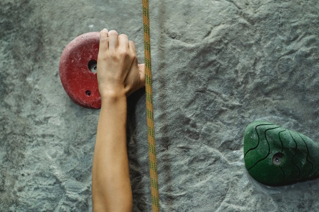 Person climbing a wall reaching up for a hand hold.
